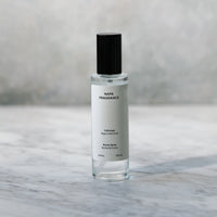 Small glass bottle with a black cap on a marble surface with a blurred background