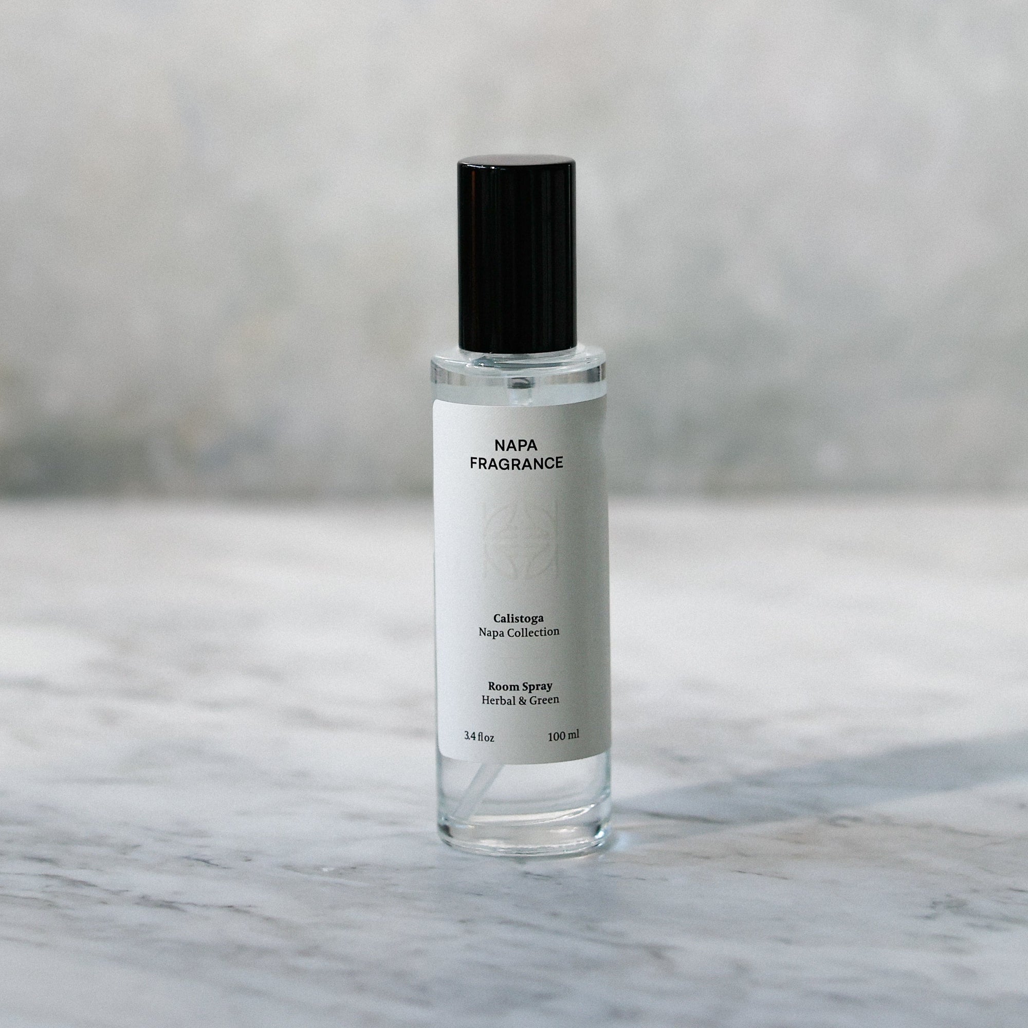Small glass bottle with a black cap on a marble surface with a blurred background
