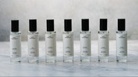 Row of seven skincare serum bottles with black caps on a marble surface.