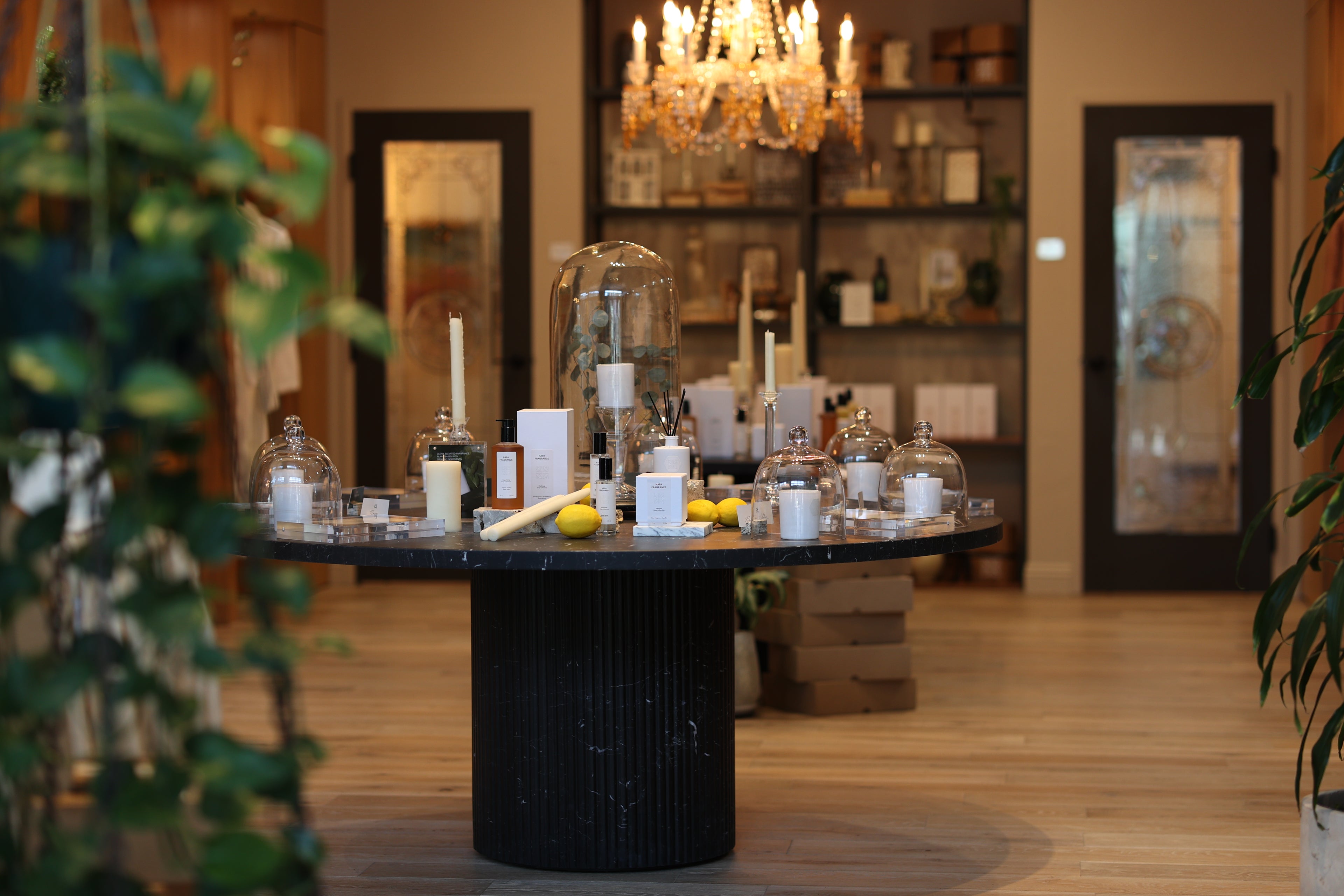 Decorative table with candles and vases in a room with shelves and mirrors.