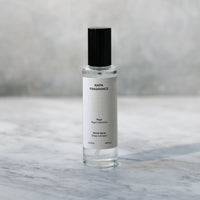 Small clear bottle with black cap on a marble surface with a blurred gray background