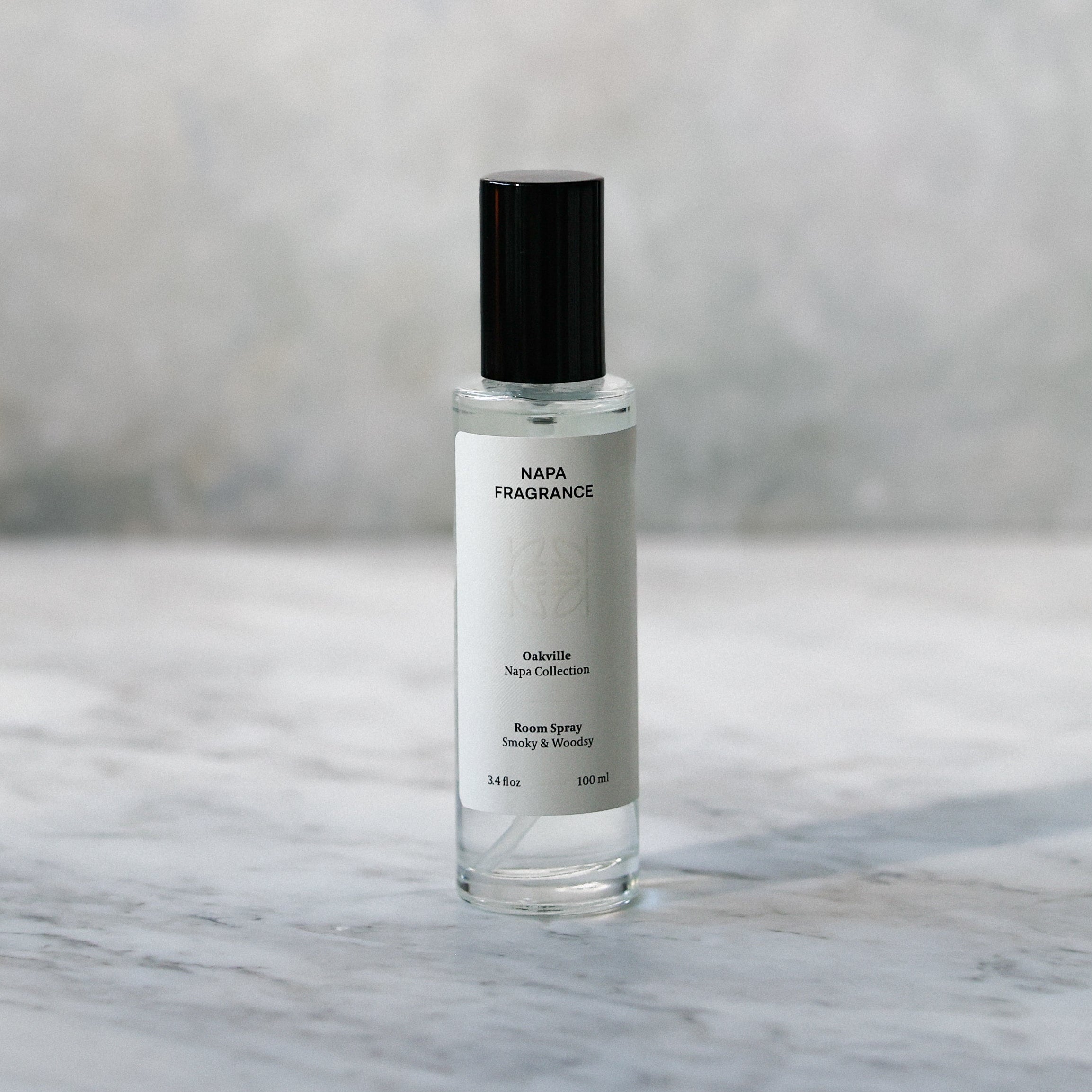 Small clear bottle with black cap on a marble surface with a gray textured background