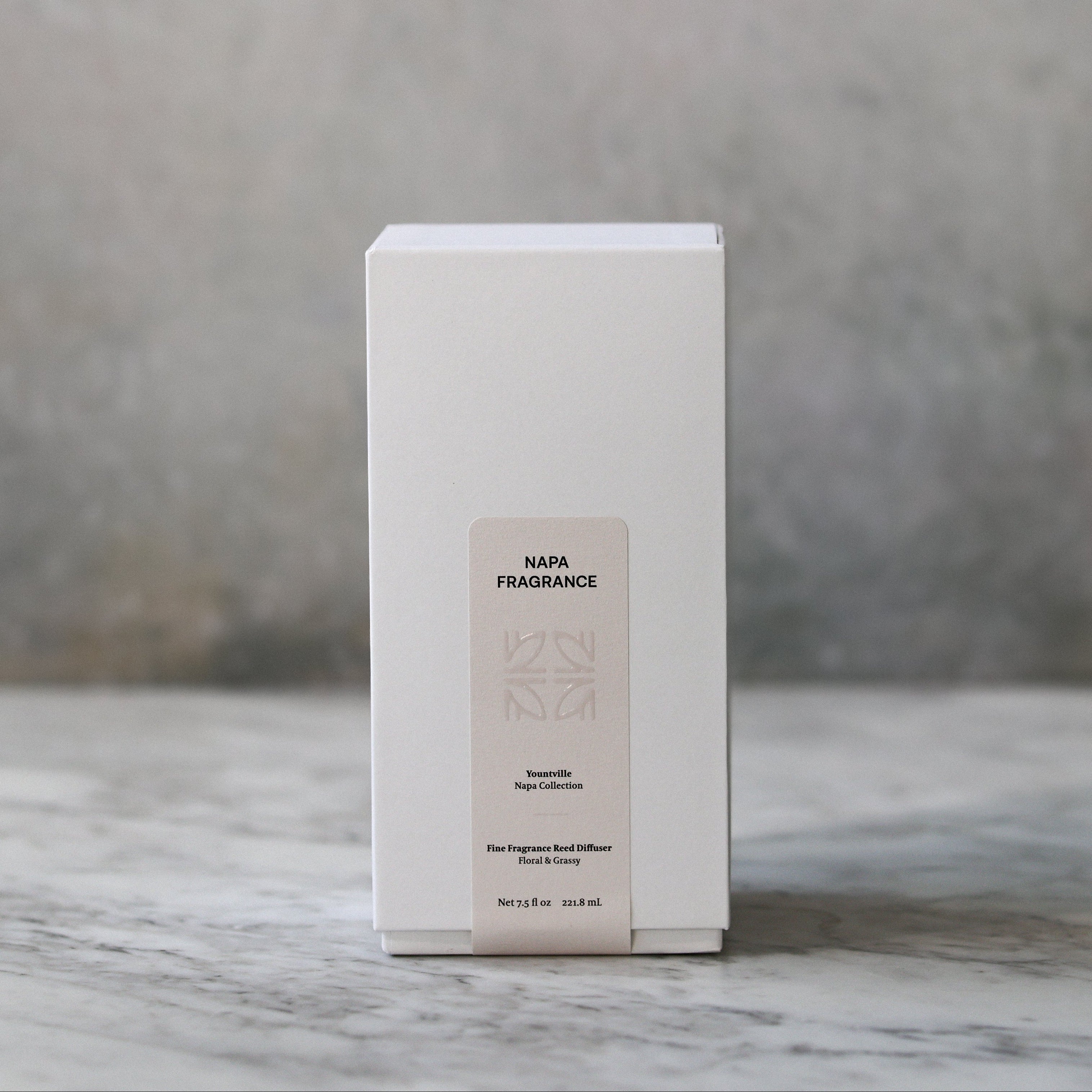 White rectangular box with a label on a marble surface and textured wall background